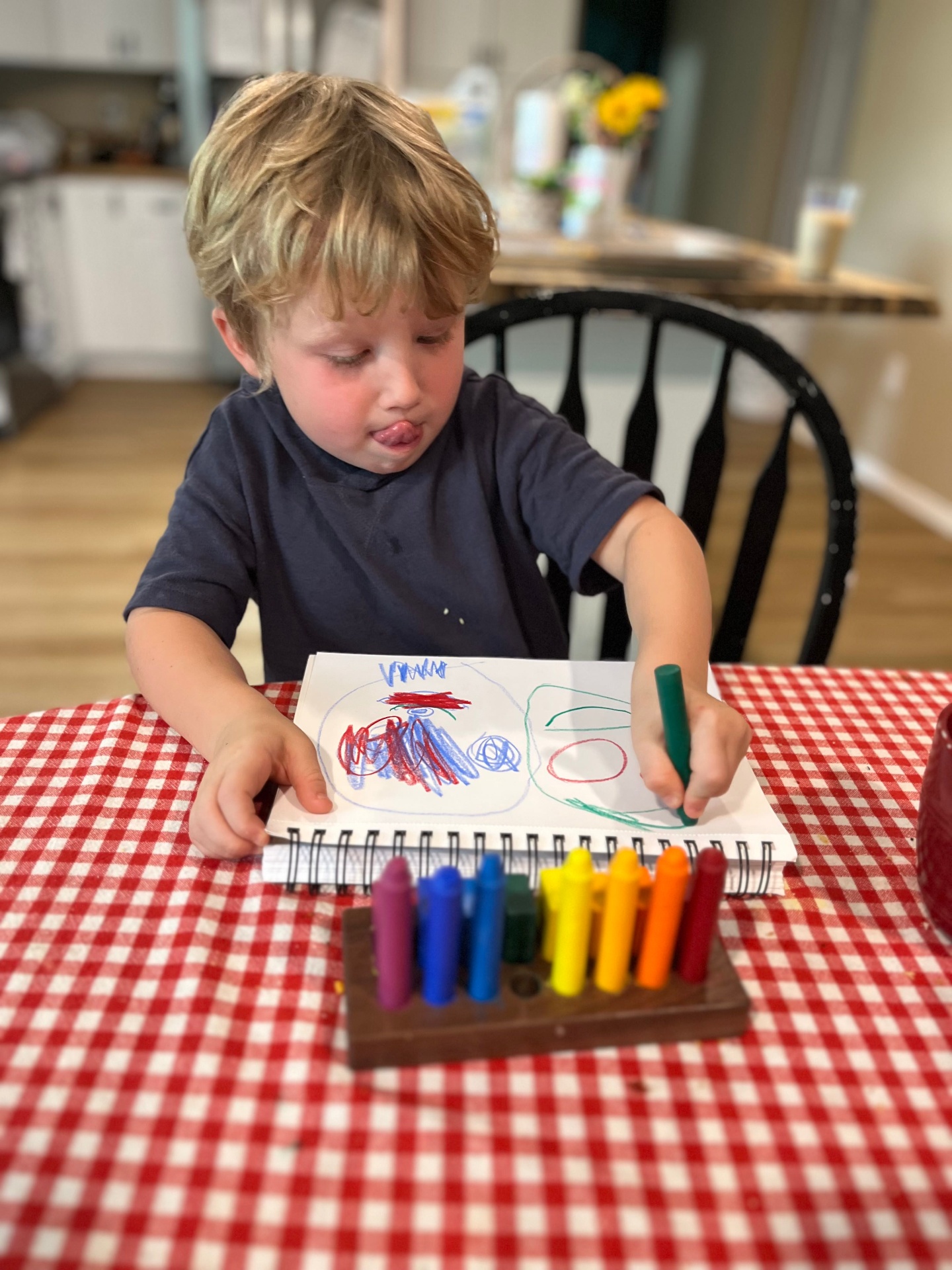 A young child drawing with crayons at the table