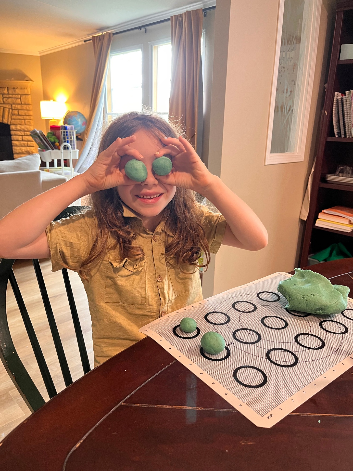 A child smiling and playing with dough at the table