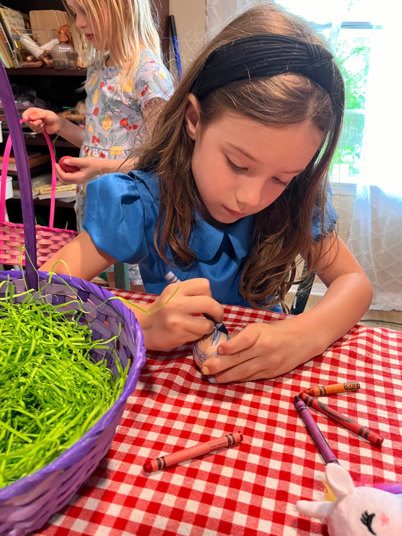 A child carefully coloring an egg at the table