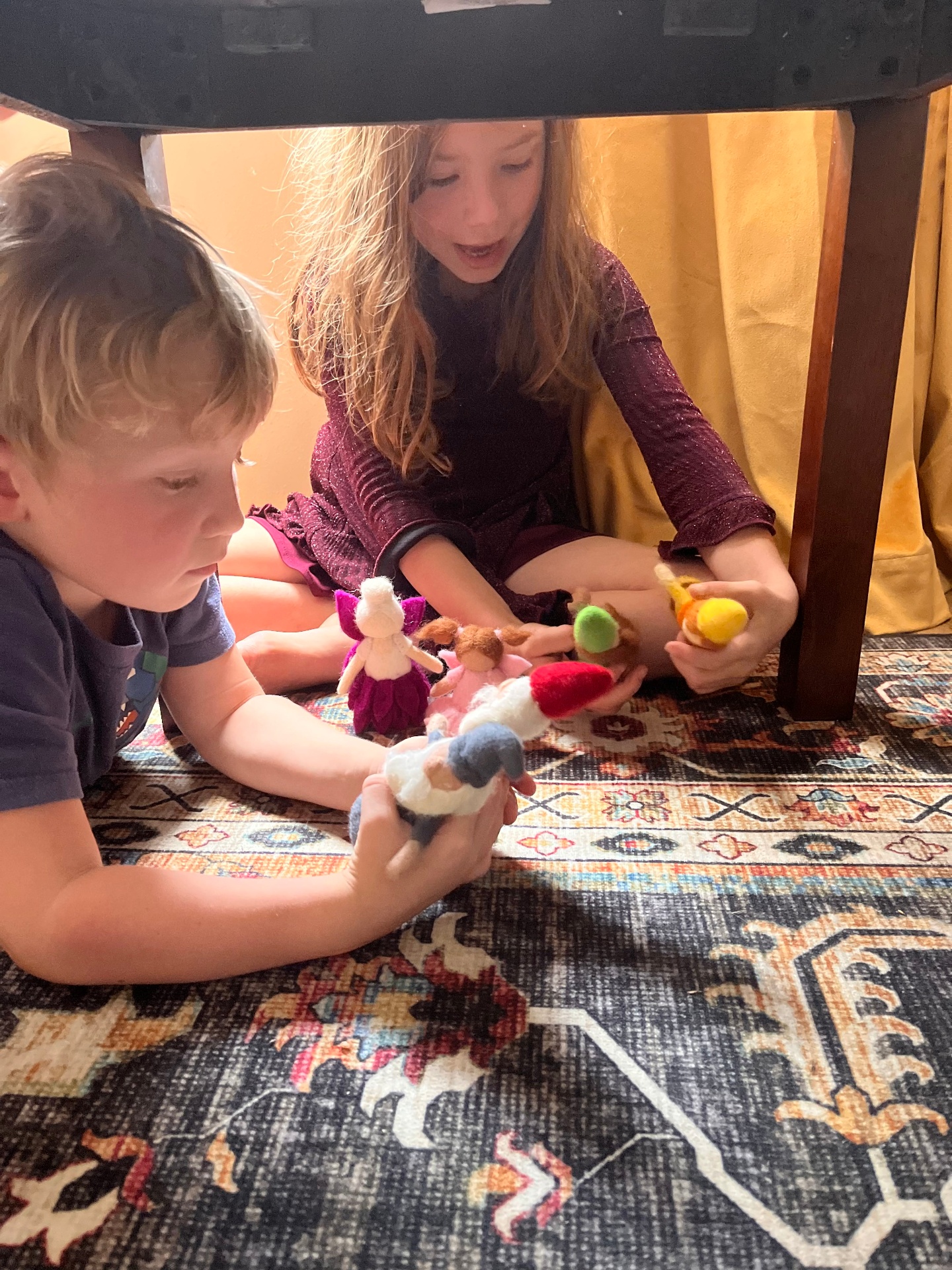 Children playing under a table with felt figures