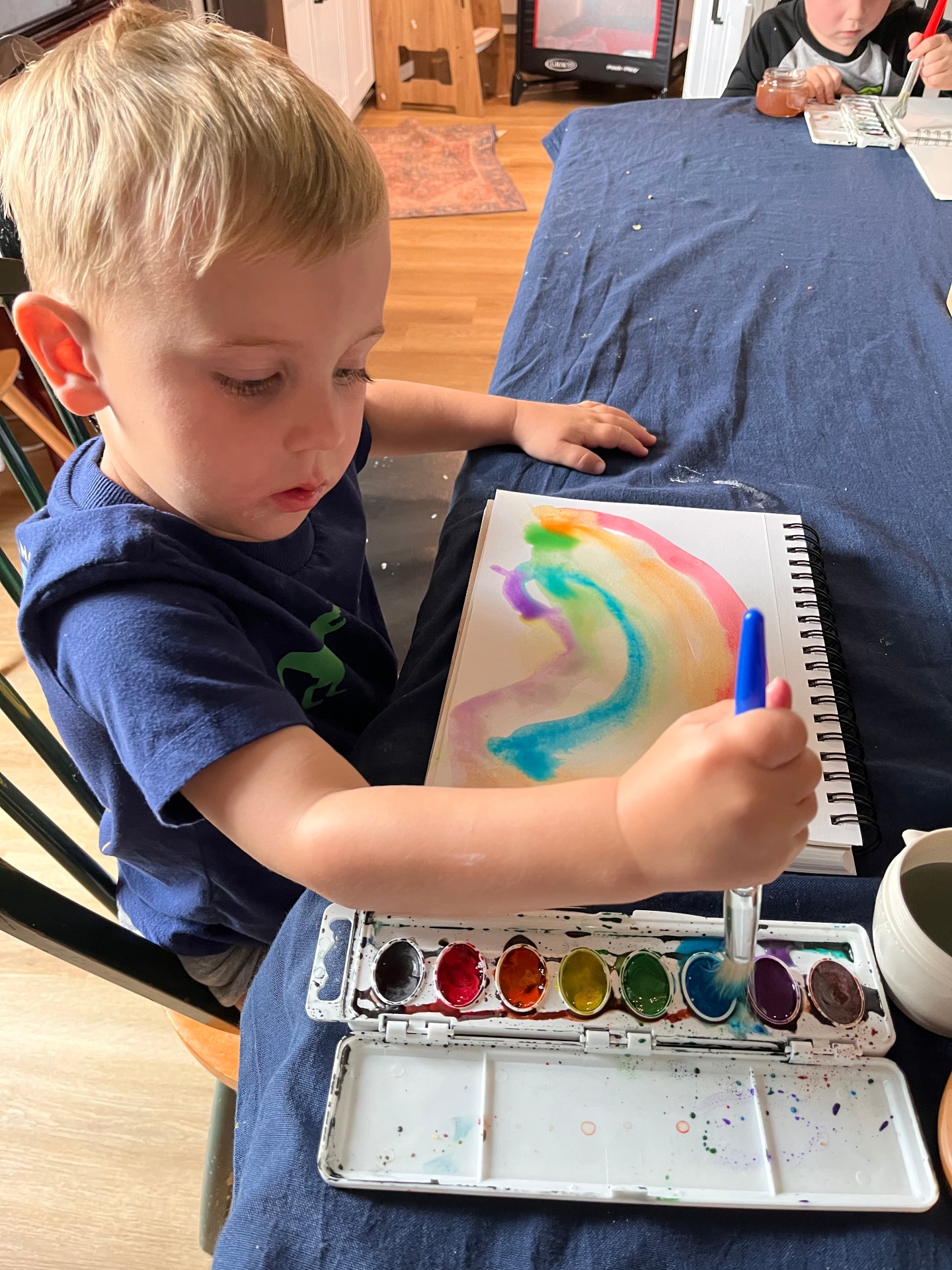 A child painting a colorful rainbow in a sketchbook