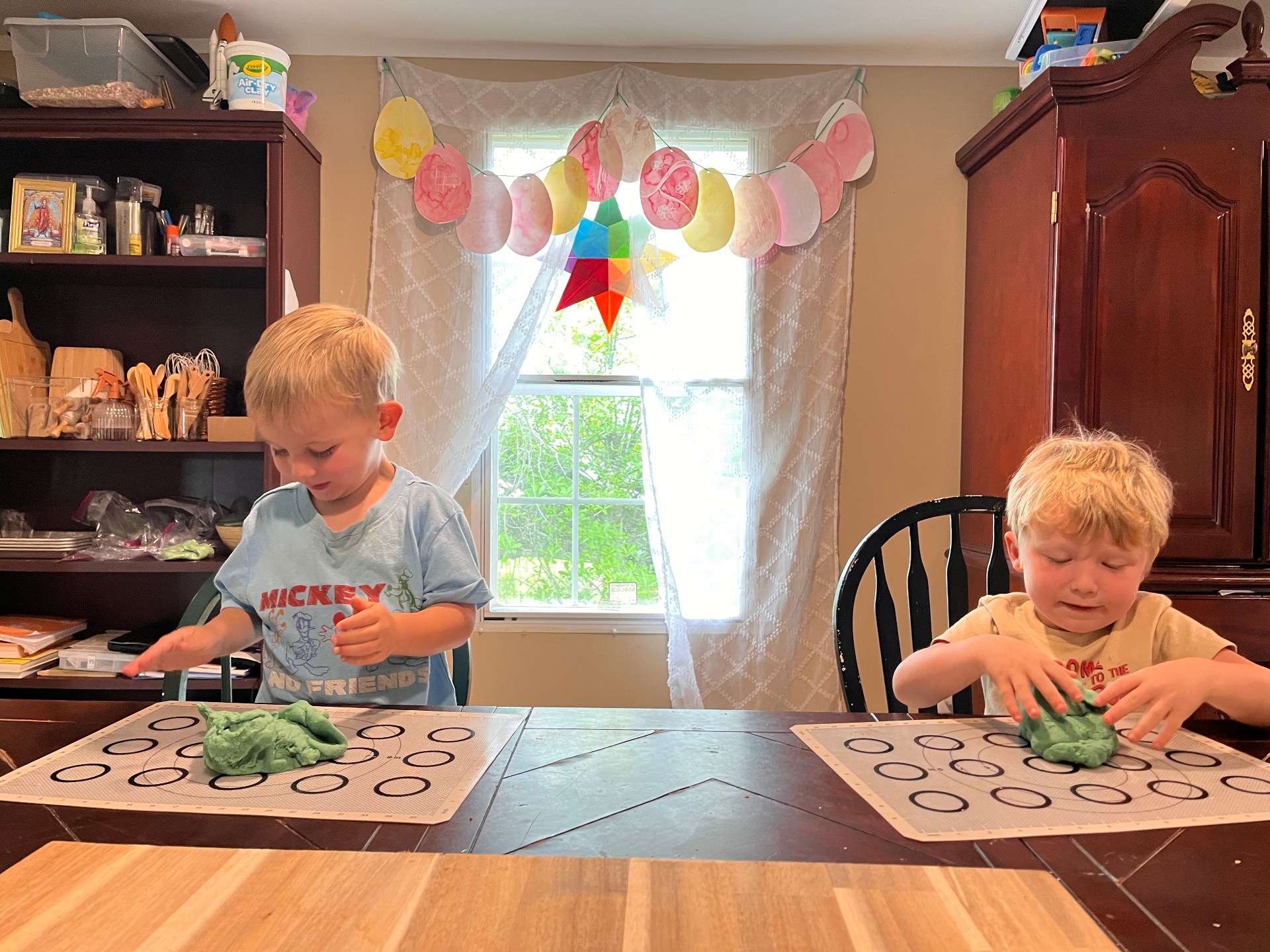 A toddler exploring dough at the table