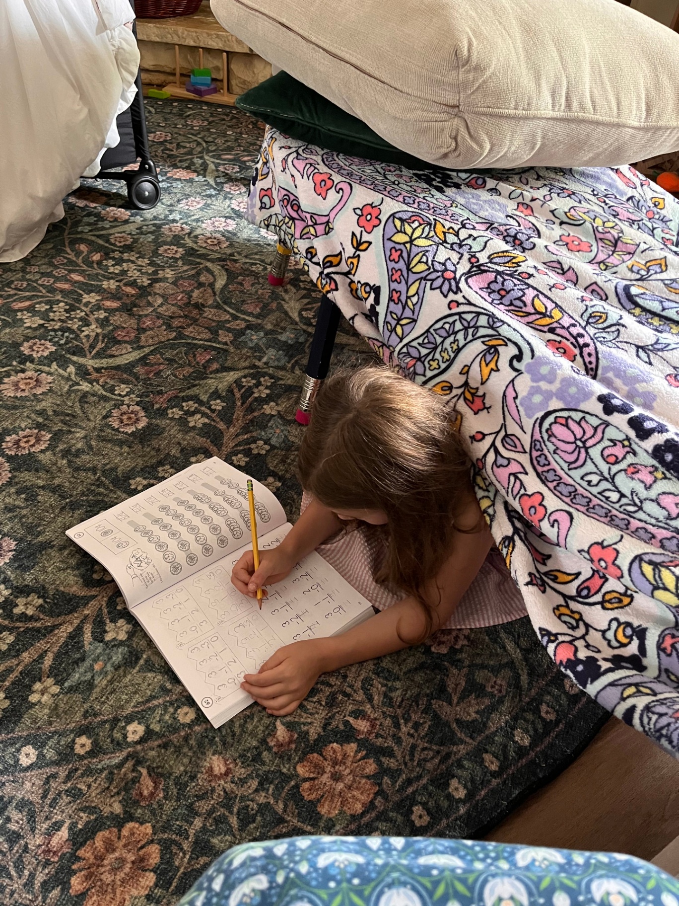 A child working independently on schoolwork under a cozy blanket fort